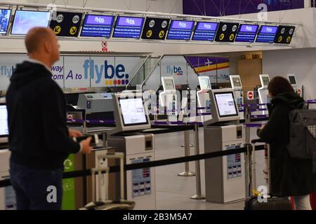 Passagiere stehen an leeren Check-in-Schaltern am internationalen Flughafen Birmingham, da Flybe, Europas größte regionale Fluggesellschaft, in die Verwaltung eingebrochen ist. Stockfoto