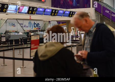 Passagiere stehen an leeren Check-in-Schaltern am internationalen Flughafen Birmingham, da Flybe, Europas größte regionale Fluggesellschaft, in die Verwaltung eingebrochen ist. Stockfoto