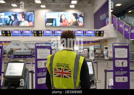 Ein Beamter der britischen Regierung steht an den leeren Flybe Check-in-Schaltern am internationalen Flughafen Birmingham, da Flybe, Europas größte regionale Fluggesellschaft, in die Verwaltung eingebrochen ist. Stockfoto