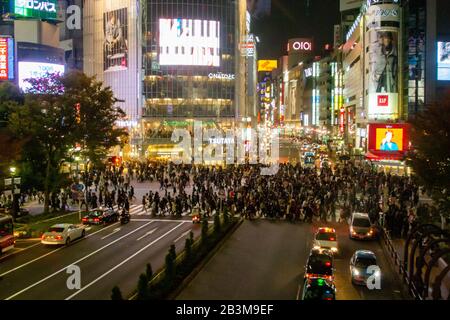 Nachtaufnahmen von Fußgängern, die eine vierstreifige Zebraüberquerung am Shibuya Crossing im Zentrum Tokios, Japan, überqueren Stockfoto