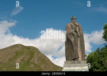 Dies ist die Statue des berühmten Schriftstellers Alexandre Kazbegi in Stephantsminda (Kazbegi), Georgia. Das Denkmal liegt am blauen Himmel und am Kaukasus Mo Stockfoto