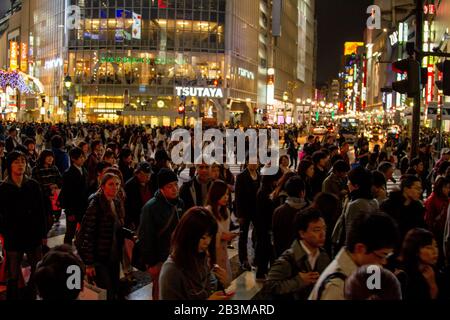 Nachtaufnahmen von Fußgängern, die eine vierstreifige Zebraüberquerung am Shibuya Crossing im Zentrum Tokios, Japan, überqueren Stockfoto