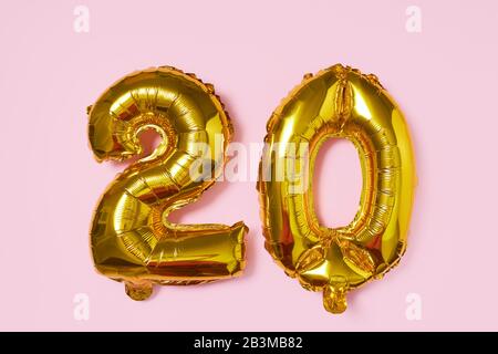 Golden Foil Ballon in Form der Nummer 20 auf pinkfarbenem Hintergrund. Cashback- oder Verkaufskonzept Stockfoto
