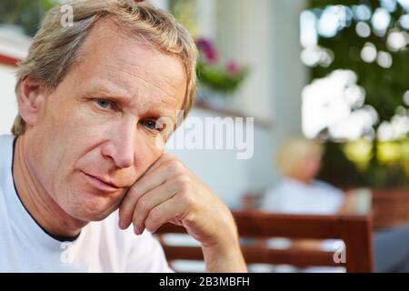 Nachdenklicher alter Mann sitzt vor seinem Haus Stockfoto