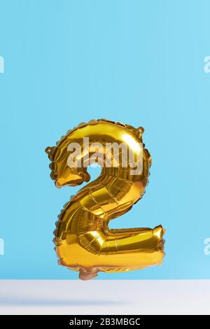 Golden Foil Ballon in Form von Zahlen auf blauem Hintergrund. Levitationseffekt Stockfoto