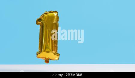 Golden Foil Ballon in Form von Zahlen auf blauem Hintergrund. Levitationseffekt Stockfoto