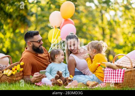 Glückliche Familie, die ein Picknick in der Natur macht.Lächelnde Familie, die im Park picknickt.Sommerzeit. Stockfoto