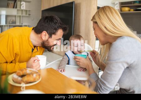 Eltern füttern Baby zusammen.Vater und Mutter füttern ihren niedlichen Babyjungen. Stockfoto