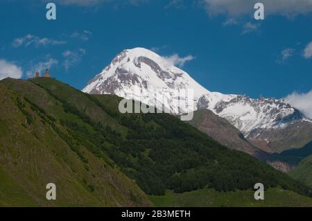 Der Berg Kazbek ist einer der höchsten Gipfel im Kaukasusgebirge. Die Gergeti Trinity Church ist das wichtigste kulturelle Wahrzeichen des Kazbegi District, Georgia. Stockfoto