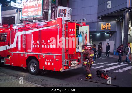 31.12.2017, Tokio, Japan, Asien - EIN Feuerwehrmann, der Schutzkleidung trägt, steht bei einem Notfall in der Innenstadt hinter einem Feuerwehrmotor. Stockfoto