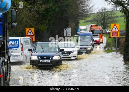 Winterbourne Abbas, Dorset, Großbritannien. März 2020. Wetter in Großbritannien. Die Fahrzeuge fahren auf der A35 bei Winterbourne Abbas bei Dorchester in Dorset durch das Flutwasser, nachdem am Morgen starker Regen die Überschwemmung verursacht hatte. Bildnachweis: Graham Hunt/Alamy Live News Stockfoto