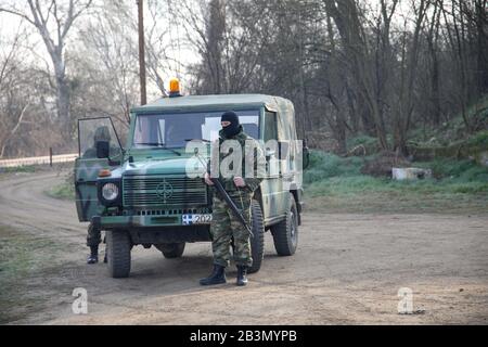 Kastanies, Evros, Griechenland - 1. März 2020: Griechische Soldaten bewachen, während sich in der Nähe des Grenztores Kastanies an der griechisch-türkischen Grenze Migranten sammeln Stockfoto