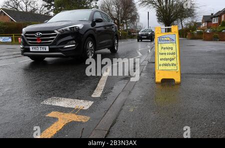 Das Parken hier könnte die Lebenszeichen eines Kindes außerhalb der Hilltop First School Windsor gefährden. Auf den Zickzacklinien sind Schilder angebracht, um das Parken zu verhindern. Stockfoto