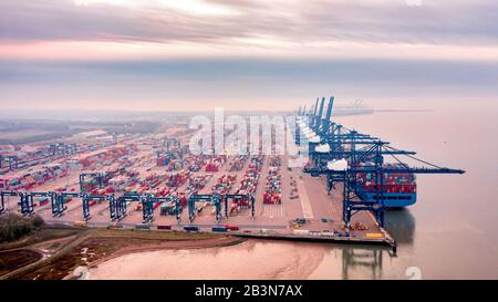 Luftaufnahme von Reihen gestapelter Transportbehälter und Ladegantrys, die unheimlich durch den Morgennebel gesehen wurden. Stockfoto