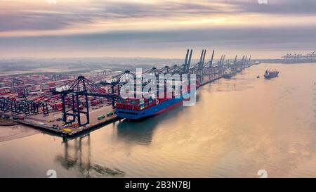 Luftaufnahme des Containerhafens Felixstowe im frühen Morgenherbstnebel, ein Frachtschiff, das mit Reihen gestapelter Container beladen ist Stockfoto
