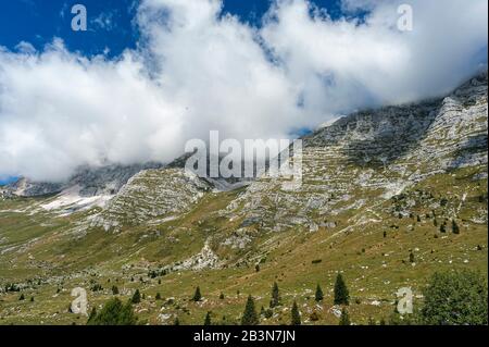 Berggipfel über dem Montasio-Plateau, im Sommer teilweise von flauschigen Wolken bedeckt. Julische Alpen im Nordosten Italiens. Stockfoto