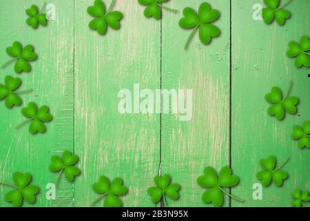 Shamrocks auf grünem Holztisch ein Symbol und St. Patricks Day. Bbanner mit Eckrand von Shamrocks. Strukturiertes Muster Stockfoto