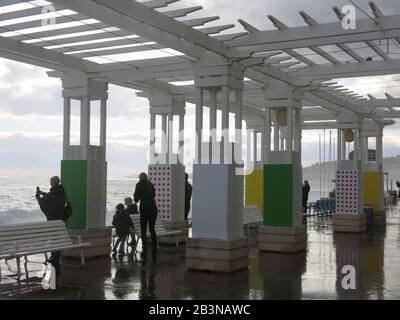 Touristen unter den Schutzhütten an der Promenade des Anglais machen Fotos von den stürmischen Meeren und den Wellen des Mittelmeers; Nizza, März 2020 Stockfoto