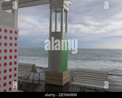 Grauer Himmel und stürmisches Meer Anfang März mit leeren Sitzplätzen an der Strandpromenade von Anglais in Nizza an der französischen Riviera. Stockfoto