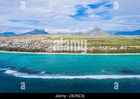Luftbild mit einer Drohne von Wellen, die am Strand von Flic en Flac mit dem Berg Piton de la Petite Riviere Noire, auf Mauritius, im Indischen Ozean und in Afrika zusammenstoßen Stockfoto