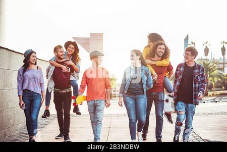 Gruppe der glücklichen Freunde Spaß im Freien - Junge Leute huckepack beim Lachen und gemeinsam zu Fuß in die Innenstadt Stockfoto