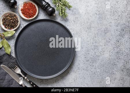 Küche leer mit schwarzer Platte, Gewürzen und Zutaten zum Kochen auf Grau. Platz für Text oder Design. Ansicht von oben. Stockfoto