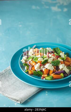 Blaue Platte mit frischen Superfoods gesunder Salat mit roter Zwiebel, Tomaten, Doucette (Lammersalat, Maissalat, Feldsalat) und Fetakäse. Hellblau s Stockfoto