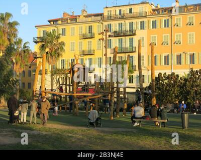 Familien genießen den Sonnenschein am Abend auf dem Spielplatz an der Promenade du Paillon im Zentrum von Nizza, Februar 2020 Stockfoto