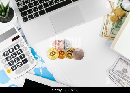 Laptop auf dem Tisch in der Nähe von Dollar und Bitcoins im Büro Stockfoto