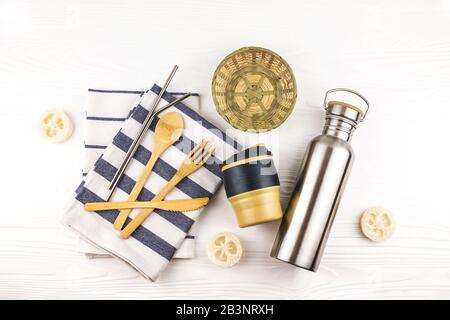 ECO-Set mit Bambusbesteck, wiederverwendbarem Kaffeebecher und Wasserflasche mit Küchenhandtüchern auf weißem Hintergrund. Nachhaltiger Lebensstil. Kein Abfall und keine Vergeudung Stockfoto