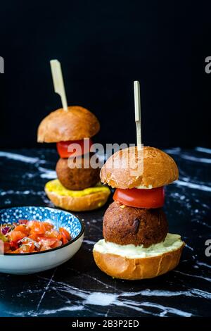 Hausgemachte mediterrane Mini Falafel Vegan Burger mit Tzatziki und Turmeric Sauce. Starteressen mit Holzstäbchen/Pico de Gallo Salat. Gesundes Organ Stockfoto