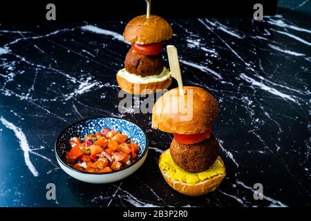 Hausgemachte mediterrane Mini Falafel Vegan Burger mit Tzatziki und Turmeric Sauce. Starteressen mit Holzstäbchen/Pico de Gallo Salat. Gesundes Organ Stockfoto