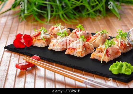 Frisches Sushi auf rustikalem Holztisch. Nahaufnahme. Kreatives Foto. Stockfoto