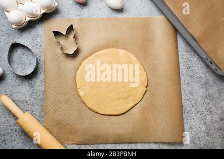 Prozess der Herstellung von Plätzchen in Form von Häschen und Eiern auf dem Tisch. Ansicht von oben. Ostern. Stockfoto