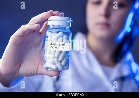 Frau hält Kiste antiviraler Medikamente. Konzeption von Studien über Coronavirus. Stockfoto