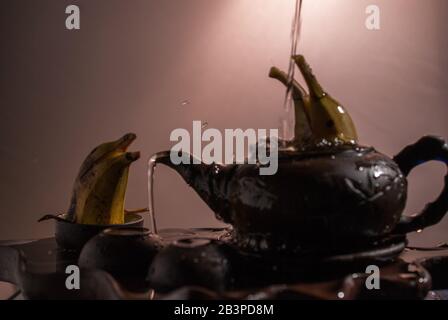 Zwei Delfine formten Bananen, die im Teakup spielen Stockfoto