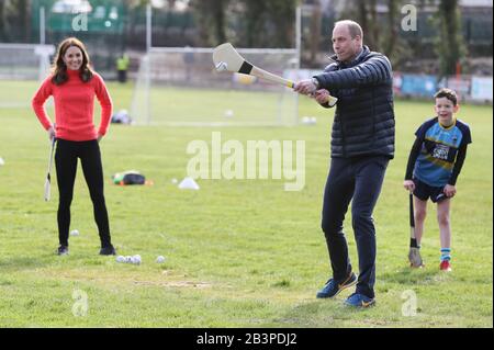 Der Herzog und die Herzogin von Cambridge versuchen während eines Besuches in einem örtlichen Gälic Athletic Association (GAA) Club zu schleudern, um am dritten Tag ihres Besuches in der Republik Irland mehr über den traditionellen Sport zu erfahren. Stockfoto