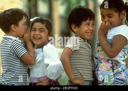 Austin Texas USA, um 1988: Kindergartners flüstern sich gegenseitig Geheimnisse auf dem Schulhof. ©Bob Daemmrich Stockfoto