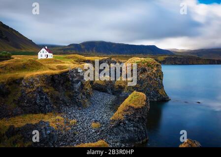 Meeresufer in Island mit Klippen und einem kleinen Haus im Dorf Arnarstapi Stockfoto