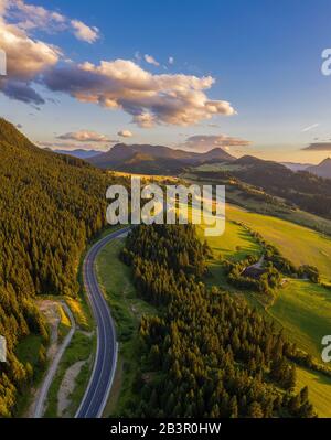 Straße, die bei Sonnenuntergang durch Wälder der Region Liptov in der Slowakei führt Stockfoto