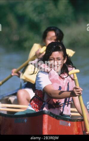 Bandera Texas USA, 1991: Mädchen der fünften Klasse, die Rettungsringe tragen, paddeln während eines nächtlichen Schulausflugs zu einem Camp im Texas Hill Country mit einem Kanu. ©Bob Daemmrich Stockfoto