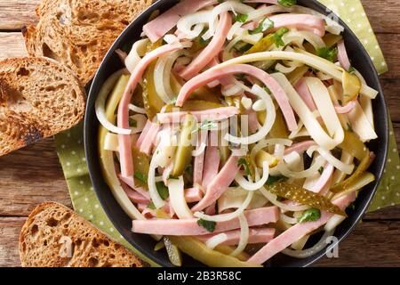 Schweizer Salat aus Wurst, Käse, Zwiebel, mit würziger Sauce gewürzt in einem Teller auf dem Tisch horizontale Draufsicht von oben Stockfoto