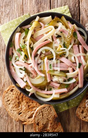 Schweizer Wurstsalat mit Käse, Zwiebeln, Beizen und Kräutern in einer Platte auf dem Tisch senkrecht von oben Stockfoto