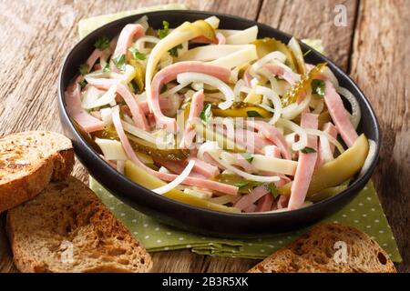 Traditioneller Wurstsalat Schweizer Wurstsalat würzt mit würziger Sauce in einem Teller auf dem Tisch. Horizontal Stockfoto