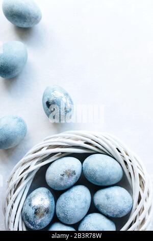 Blaue Ombre-Eier auf hellem Hintergrund im weißen Gelege. Frühlingsblumen. Tageslicht. Stylische, minimale Kompositionen in Pastellfarben. Osterkonzept. Flache Lage, Draufsicht. Kopierbereich. Stockfoto