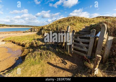 Ein geschnitztes Eingangstor zur Insel Llanddwyn mit Newborough Beach im Hintergrund, Anglesey Stockfoto