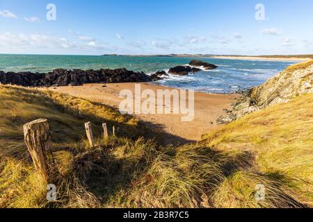 Ein kleiner Strand auf der Insel Llanddwyn mit Blick auf Malltraeth Beach, Anglesey Stockfoto