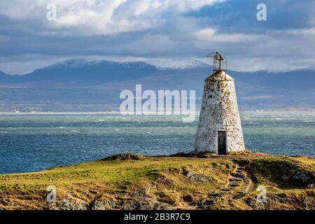 Der Leuchtturm Twr Bach auf der Insel Llanddwyn mit schneebedeckten Snowdonia Bergen im Hintergrund, Anglesey Stockfoto