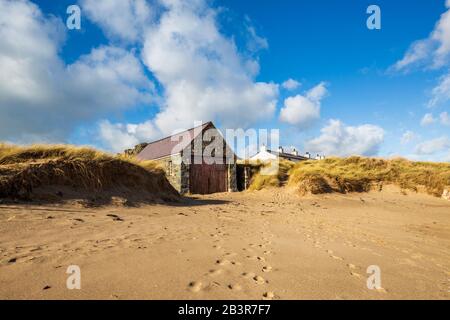 Das Rettungsschwimmhaus und die Dächer der weißen Cottages des Piloten vom Strand auf der Insel Llanddwyn, Anglesey Stockfoto