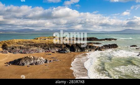 Ein Blick auf Twr Bach und die schneebedeckten Snowdonia Berge über Porth Twr Mawr auf Llanddwyn Island, Anglesey Stockfoto